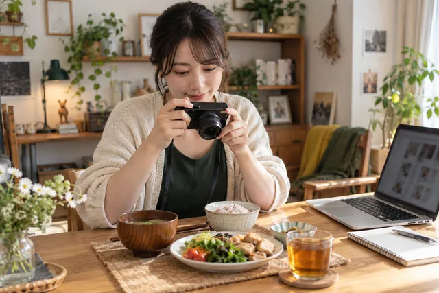 自作の料理をカメラで撮影し、ブログの内容を考える人