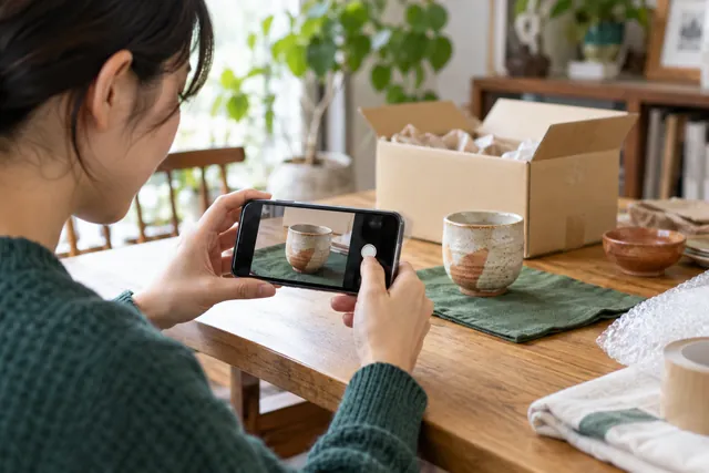 出品するカップをスマートフォンで撮影する手元