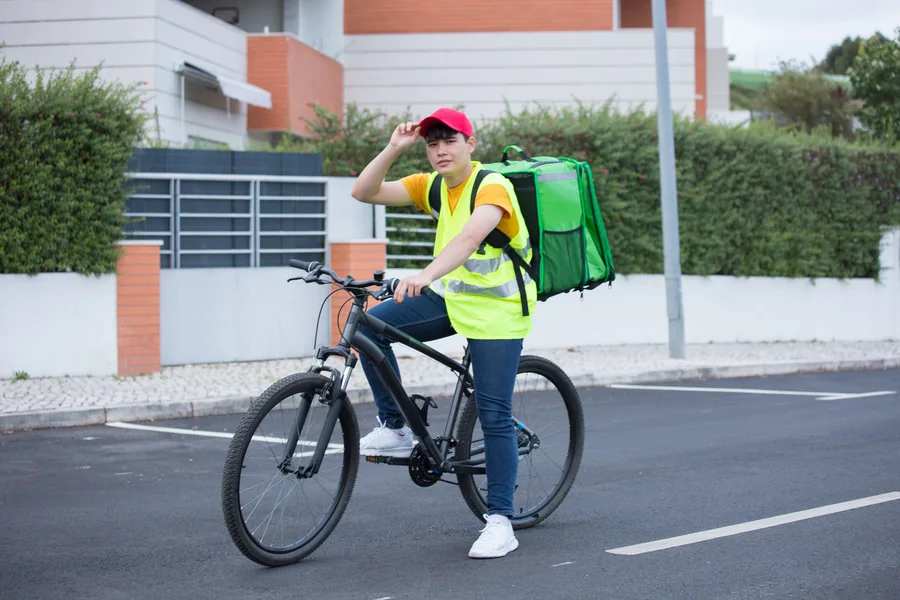 保温バッグを背負って自転車に乗る配達員