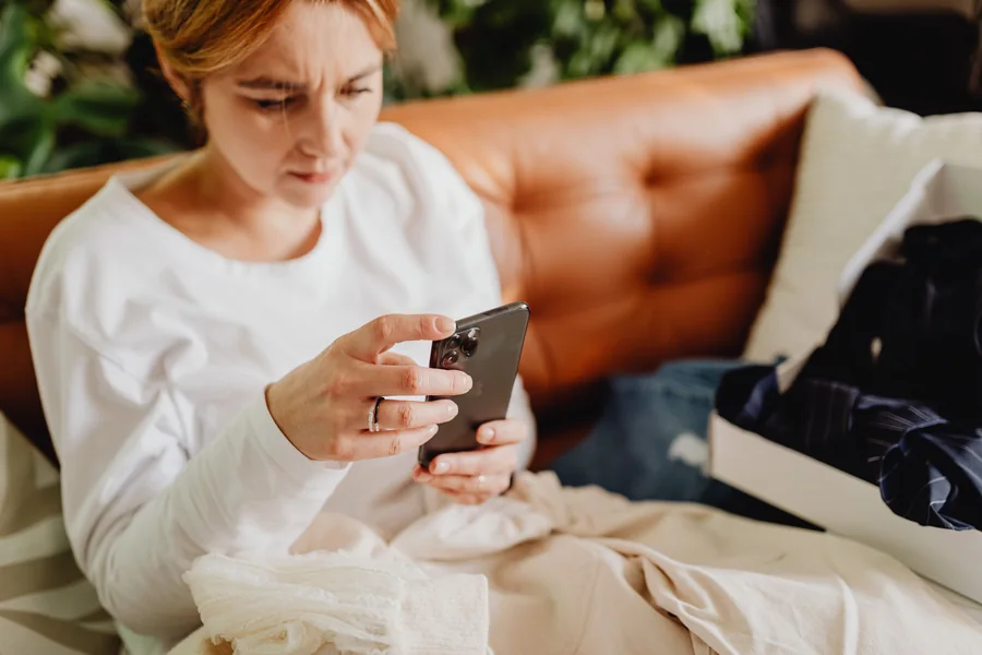 自宅のソファでスマートフォンを操作する女性