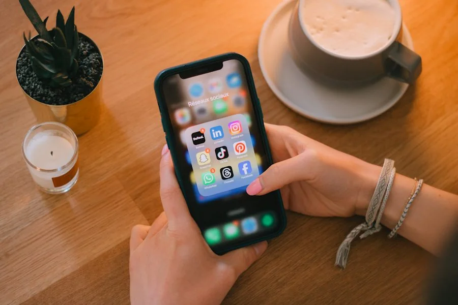 コーヒーのある机でSNSアプリをスマートフォンで操作する手元